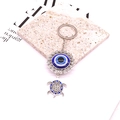 Detailed close-up of tribal silver turtle keychain with blue nazar evil eye and crystals - Turtle Shape / Silver/Blue