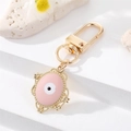 Pink evil eye charm keychain with golden alloy frame and floral details on white stone - Oval Pink Enamel (K200)