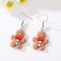 Detailed close-up of gingerbread man earrings with red bow on a white floral background - Brown Gingerbread Man