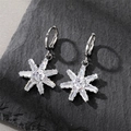 Detailed macro view of silver star earrings with clear cubic zirconia on stone background - Heptagon Hoop