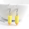 Creative yellow pencil resin dangle earrings with silver hooks shown on a ceramic bowl - Yellow
