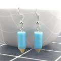 Detailed close-up of creative blue pencil resin earrings with metal hooks on a white grid - Light Blue