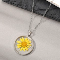 Macro detail of round resin pendant with yellow daisy flower and silver flakes - Yellow