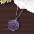Detailed close-up of a round silver necklace featuring a real purple dried daisy flower - Purple