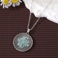 Close-up of handmade round pendant necklace with preserved light blue dried flowers - Blue Gypsophila Silver
