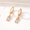 Detailed macro view of gold-plated square lavender crystal drop earrings on white fabric - Purple