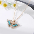 Elegante Schmetterlingskette in Gold mit blauen Kristallen auf weißem Marmorständer - Blau