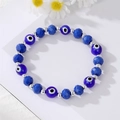Blue Evil Eye beaded bracelet with silver metal spacers and faceted crystals on white daisy background - Blue