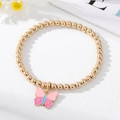 Detail of golden beaded elastic bracelet featuring a colorful enamel butterfly pendant - Pink Butterfly Bracelet