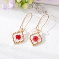 Vue détaillée de boucles d'oreilles cœur dorées avec fleurs séchées rouges et feuilles d'or - Boucles d'oreilles géométriques à fleurs séchées rouges / Rouge