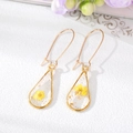 Dettaglio di orecchini in resina a goccia con fiori gialli essiccati e foglia d'oro - Giallo