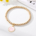 Chic gold beaded bracelet featuring a cute pink enamel smiley face charm for women - Pink Smiley Face Bracelet