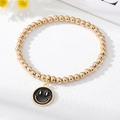 Charming gold-plated beaded bracelet featuring a classic smiling face charm on white surface - Black Smiley Face Bracelet