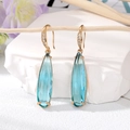 Gros plan sur les boucles d'oreilles en cristal bleu clair doré sur une branche - Rose bonbon