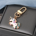 Detail eines weißen Einhorn-Anhängers mit bunter Mähne und goldenem Karabinerverschluss - Lila und Rosa Einhorn