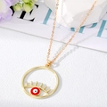 Collier doré tendance avec pendentif œil maléfique et cils sur fond de marbre - Mauvais Œil Rouge et Blanc