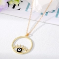 Vue détaillée du collier pendentif œil maléfique doré avec cils sur fond texturé blanc - Mauvais Œil Noir et Blanc