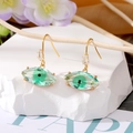 Pendientes de Ojo Turco con cristales verdes y acabado dorado sobre roca blanca - Ojos Verdes