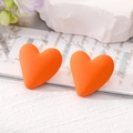 Vibrant orange matte heart stud earrings on a textured background with floral accents - Orange