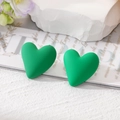 Close-up of matte green heart stud earrings on white marble and magazine background - Dark Green