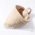 Detailed view of soft cotton muslin baby bib with white pom-pom trim and snap fastener - Light Coffee