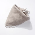Close-up of light brown cotton baby bib with decorative white pom-poms on the edges - Gray