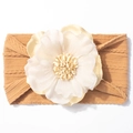 Détail d'un bandeau pour bébé en tricot jaune moutarde avec une fleur en soie crème - Café