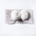 Detail of baby knitted headband featuring cream wool texture and embroidered bow design - Beige