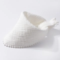 Detailed macro view of white cotton gauze baby bib with soft pom-pom trim and snap button - White