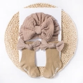 Flat lay of knit baby hat and socks set with bows on a woven mat with white background - Coffee