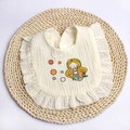 Detail of baby muslin cotton bib with ruffled edges and mermaid print on woven mat - Beige Mermaid