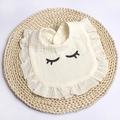 Close-up of cotton gauze baby bib featuring eyelash pattern and ruffled edges - Beige Eyelashes