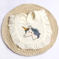 Close-up of cotton baby bib with ruffles, unicorn print, and snap button on straw mat - Beige Unicorn