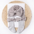 Detailed close-up of grey knitted baby turban and socks set with large bow decorations - Gray