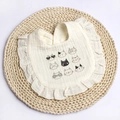 Close-up of baby bib with ruffled edges and cute cartoon cat patterns on cotton fabric - Beige Cat