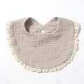 Close-up of cotton baby bib with decorative lace edges and a secure snap button closure - Gray