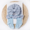 Close-up of light blue baby turban hat and matching bow socks on a woven mat base - Blue