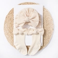 Detailed view of knitted baby hat and socks set with bows on a rustic tray - Beige