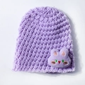 Detailed close-up of purple knit baby hat with soft yarn texture and cute rabbit plush toy - Purple