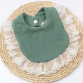 Detail of dark green waffle knit baby bib with elegant white lace trim on woven mat - Light Green