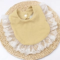 Detail of baby mustard yellow waffle bib with delicate white lace trim and button closure - Beige