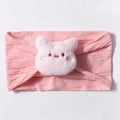 Close-up of pink knitted baby headband featuring a soft plush pig doll detail - Pink