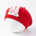 Close-up of red knit baby beret with a cute white plush bunny and bow decoration - Red