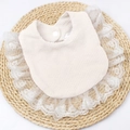 Detail of baby bib showing waffle cotton texture, lace edge, and snap button closure - White