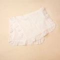Macro shot of layered soft cotton muslin baby burp cloth with delicate ruffle edges - White