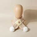 Détail de l'écharpe en tricot pour bébé avec pompons blancs et fleur en tulle jaune - Beige