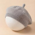 Detailed close-up of light gray knitted baby beret with ribbed edge and stem top - Gray