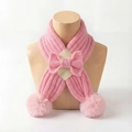 Detailed view of pink knitted baby scarf with ribbed texture, bow, and soft pom-poms - Pink