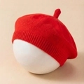 Detailed texture of red knitted baby beret with ribbed edge and top stem detail - Red
