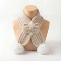 Detail of beige knit baby scarf featuring large white pom-poms and a cute bow tie - Beige